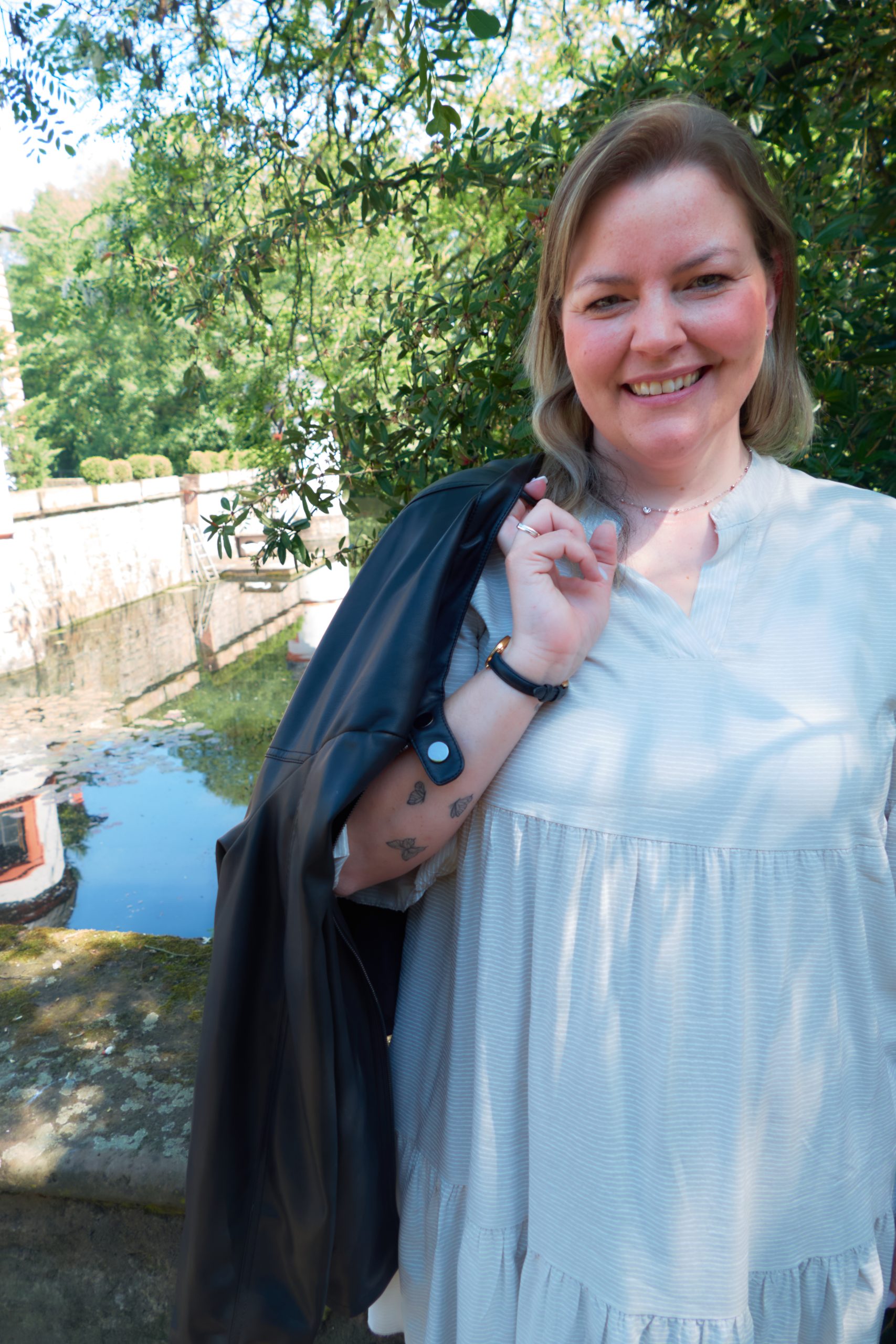MissDetail.PHOTOGRAPHY-Motherhood Fotoshooting - Frau mit Lederjacke über Schulter und Schmetterlingtattoo auf Arm vor Schlossgraben